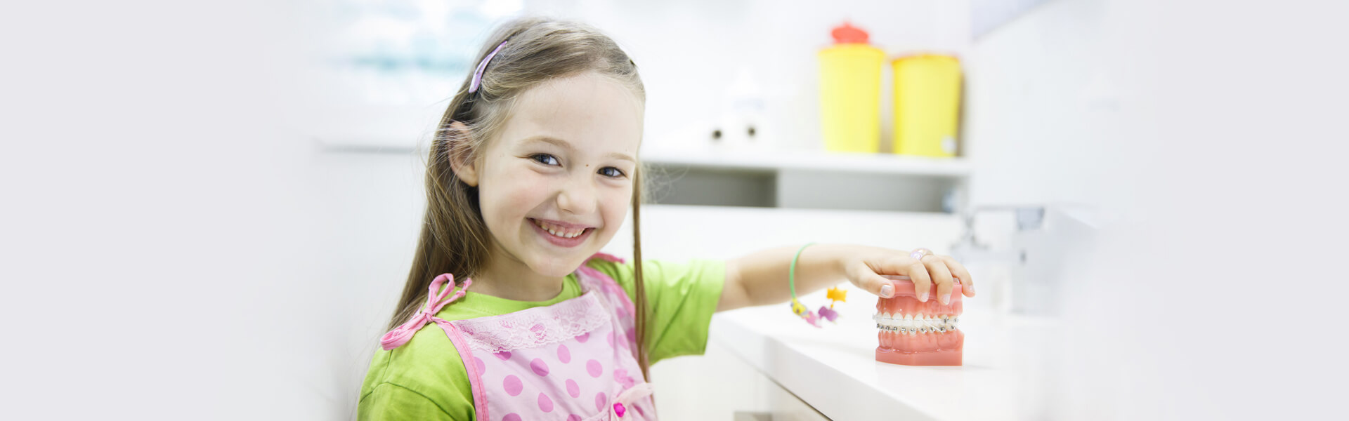 Smiling child holding dental model during pediatric dental care in Cambridge