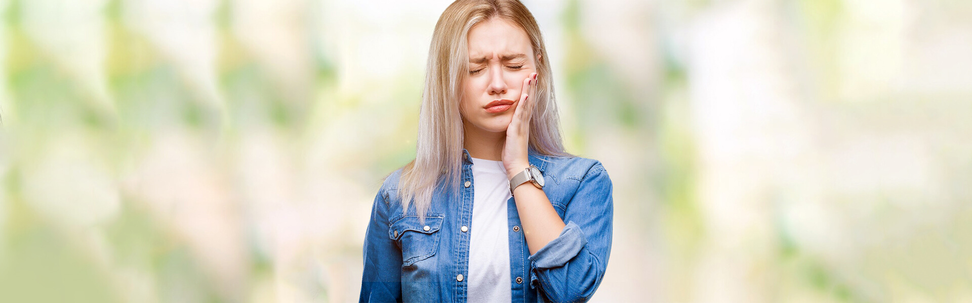 Young woman with toothache needing emergency dentistry in Cambridge