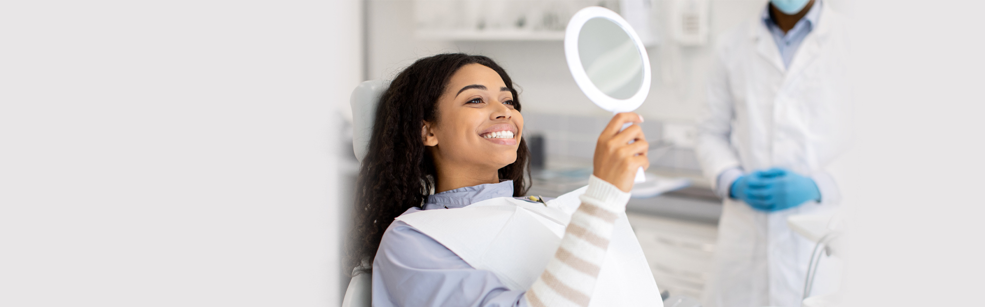 Happy woman checking her smile after root canal recovery in Cambridge