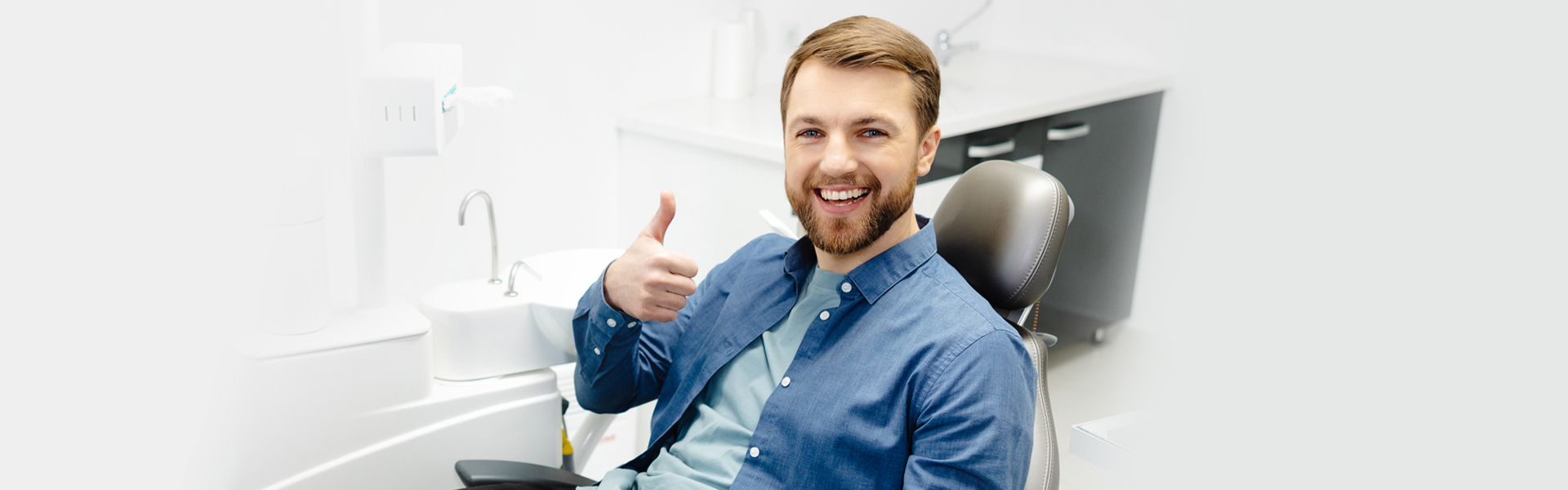 Happy male patient giving thumbs up after dental exam and X-rays.