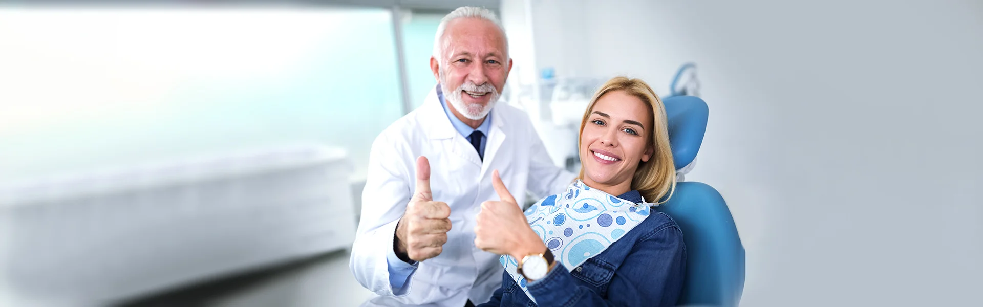 Smiling dentist and patient giving thumbs up after dental cleaning.
